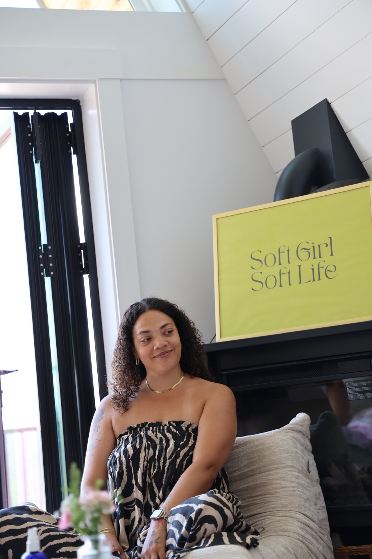 Tiana seated in a soft, sunlit room beside a Soft Girl Soft Life print, during an ALIGN workshop at the Soft Girl Soft Life Retreat